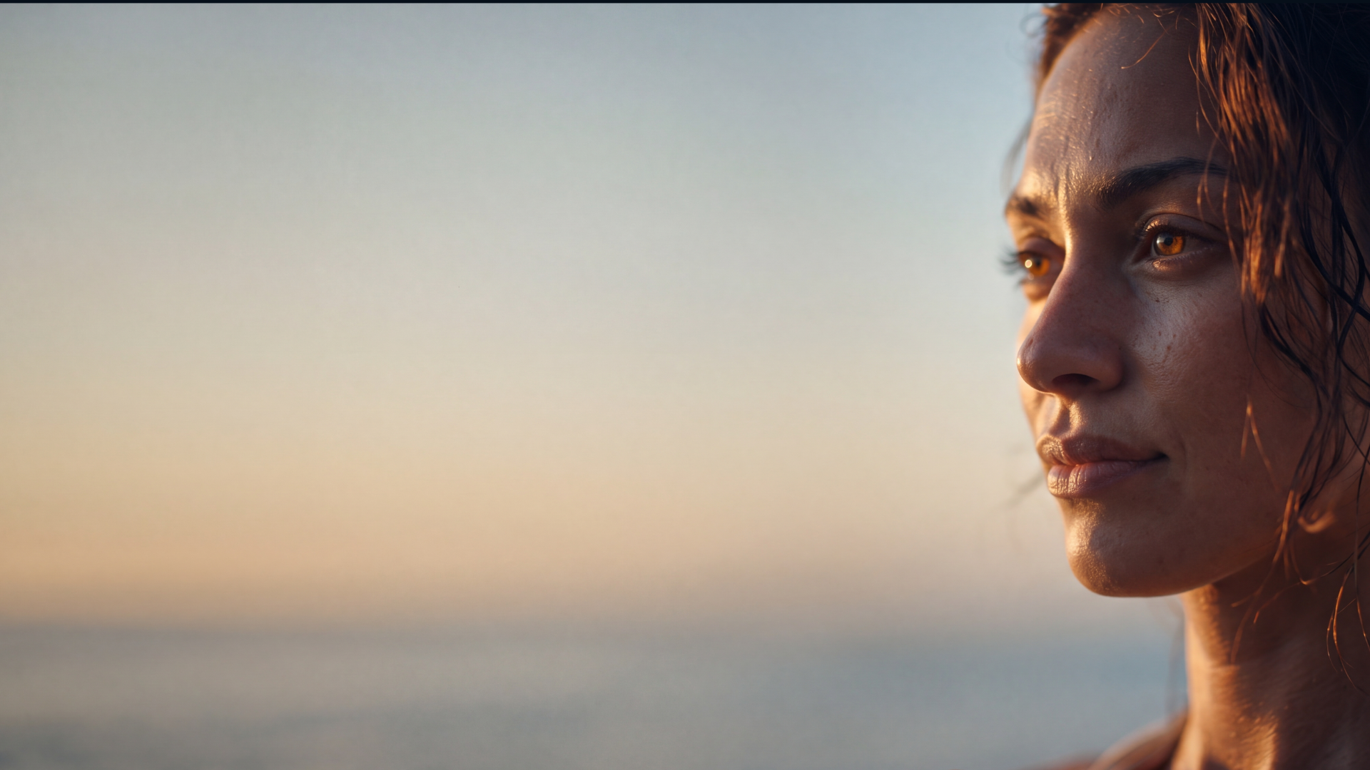 Mulher de olhos castanhos olhando para o horizonte ao pôr do sol