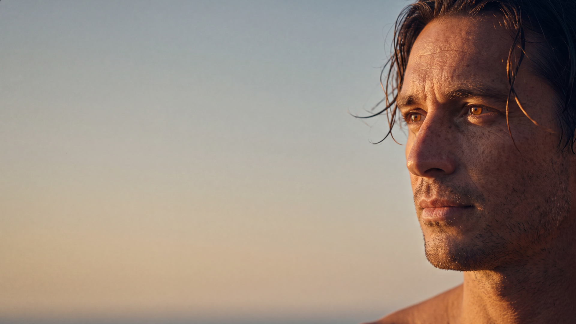 Homem de olhos castanhos olhando para o horizonte ao pôr do sol